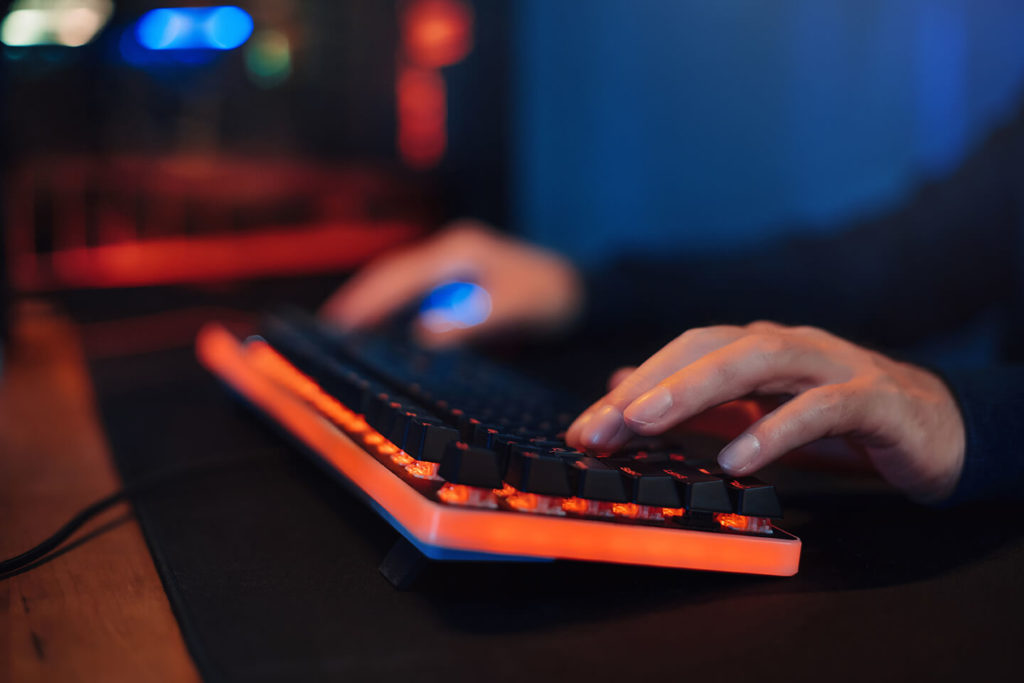 Hånden til en gamer plassert på toppen av et tastatur mens personen spiller spill. 